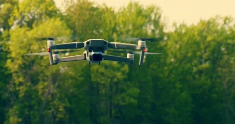 Drone hovering on a forest background as its camera points directly at you Stock Footage 132776164