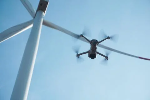Drone hovering next to the blades of a wind turbine. The integration of mod.. Stock Photos