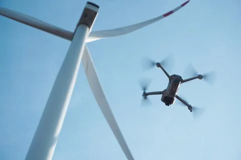 Drone hovering next to the blades of a wind turbine. The integration of mod.. Stock Photos
