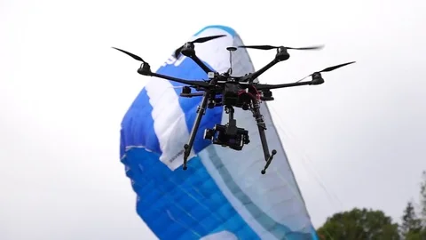 Drone hovering next to parachute Stock Footage 76046636