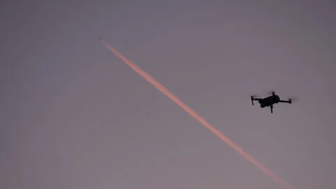 Drone hovering in twilight with visible passenger aircraft contrail Stock Footage 330174815