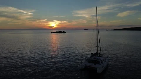 Drone hovers as catamaran slowly moves with the current during sunset Stock Footage 337093098