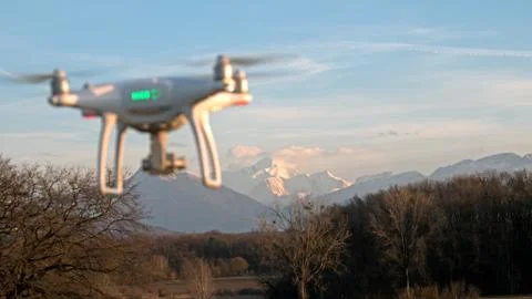A drone hovers in flight in front of the mountains of the alps in France. Stock Photos