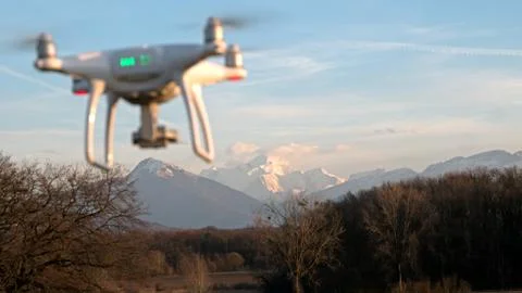 A drone hovers in flight in front of the mountains of the alps in France. Stock Photos