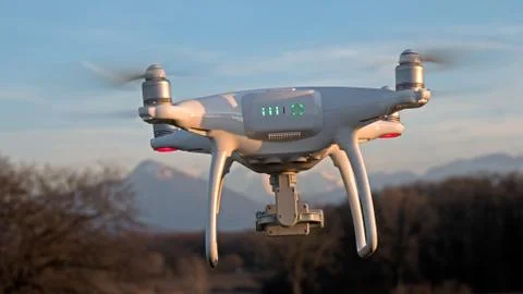 A drone hovers in flight in front of the mountains of the alps in France. Stock Photos