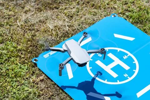 The drone hovers over the blue landing pad on the grass, the plastic propelle Foto stock