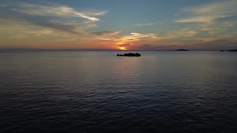 Drone hovers over water with a small island in view during sunset Stock Footage 337093158