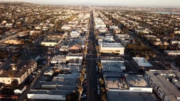 Drone hovers then descends over California beach town boulevard near sunset 库存影片 86129559