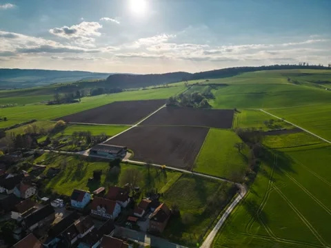 Drone hyper lapse with a village, green farmlands, hills and  blue sky Stock Footage 239279284
