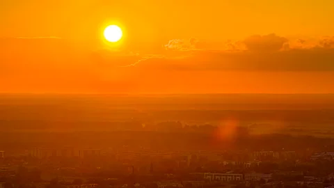 Drone hyperlapse of bright orange sunset over distant city skyline with glowing Stock Footage 313866417