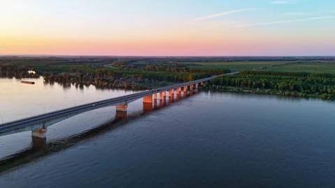 Drone Hyperlapse Over Long River Bridge Into Farmland at Sunset 動画素材 308454087