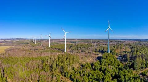 Drone image of a wind farm with towering wind turbines in a forest patch under 스톡 사진