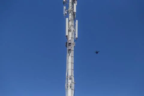 Drone inspecting a cell tower on the lower right Stock Photos