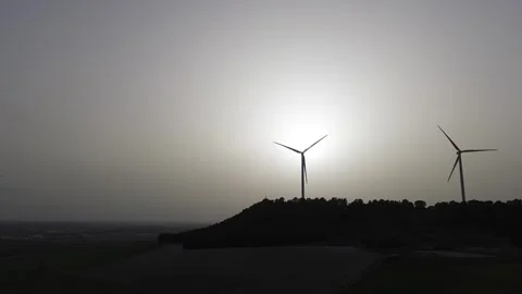 Drone lateral tracking shot of wind turbines at sunset in hazy sky Stock Footage 331284264