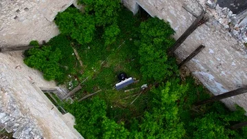 Drone lifting up above destroyed building with a man playing piano inside the ru Stock Footage 85584352