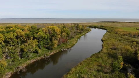 Drone looking along a wide river and moving towards a lake with colored trees. Stock Footage 116753208