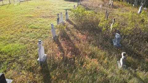 Drone looking down at a cemetery with autumn colored grass. Long shadows from Stock Footage 319595726