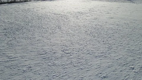 Drone looking down onto a snow covered farm field with snowdrifts. Stock Footage 221190690