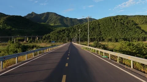 Drone low-altitude tracking shot flying forward along a scenic mountain highway Stock Footage 336610378