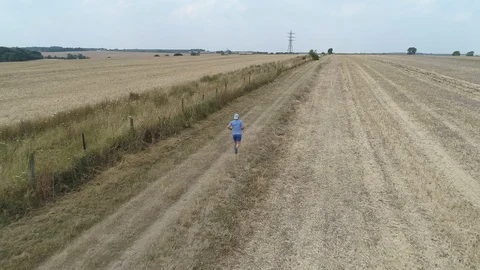 Drone Low Dolly Shot From Behind Of Man Running In Field Stock Footage 92924140