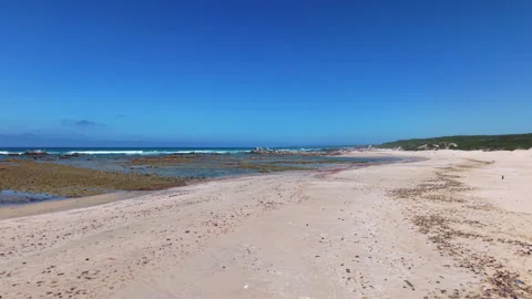 Drone Low Down on Beach Pulling Back and Ascending to Reveal Person Walking on B Stock Footage 306331022