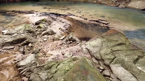 Drone low flying over a clear forest stream with mossy rocks. 動画素材 336982756