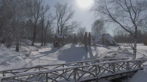 Drone low shot over a small wooden bridge in a village covered with snow Stock Footage 221389804