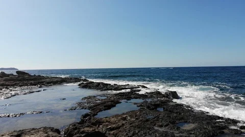 Drone low slow sweep across rocks and waves 動画素材 128996100