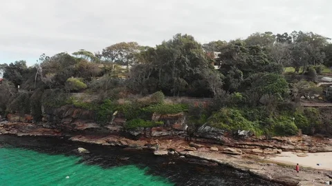 Drone lowering over water with men rock fishing in crystal clear water Stock Footage 99325162