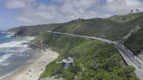 Drone lowers in epic shot of Wilderness Beach with paragliders on a sunny day Stock Footage 326769813