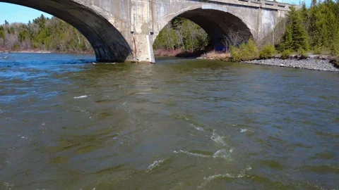 Drone making a low pass under a concrete arch above the Mitis River. Stock Footage 311202814