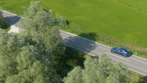DRONE Modern self steering car drives past the vibrant green meadows in Slovenia Stock Footage 114667779