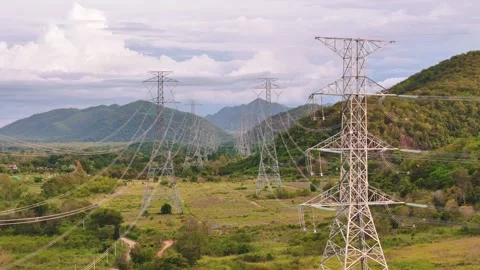 Drone motion back between high voltage transmission towers through a mountain Stock Footage 314762282
