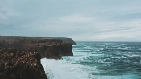 Drone moves above wild waves crashing into ocean coastal cliffs Stock Footage 203598015