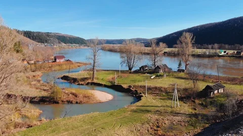 The drone moves over a small winding river, which flows into a large river. Stock Footage 106275950