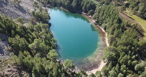 Drone moving backwards over Green Lochan (Lochan Uaine) in Glenmore Cairngor Stock Footage 169498011