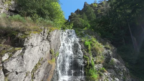 Drone moving down along a beautiful mountain cascade falling over rocks in slow  Stock Footage 333050623