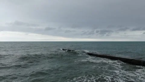 Drone moving forward above sea waves and pier under cloudy sky, D-Log footage Vidéo 321017999