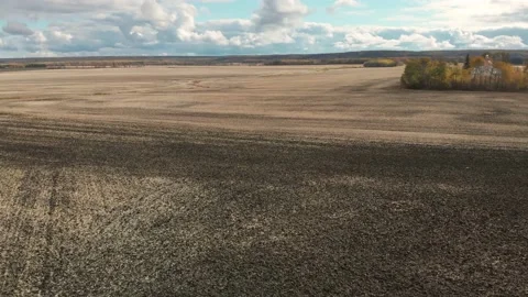 Drone moving forward just above a large recently tilled field Stock Footage 142318573