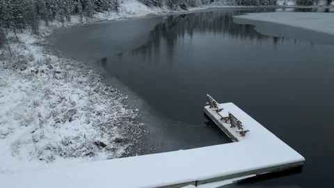 Drone moving forward low above a small partially frozen lake that has a dock Stock Footage 257723658