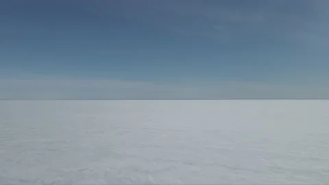 Drone moving forward over a vast frozen lake that is covered with snow and ice. Stock Footage 151652133