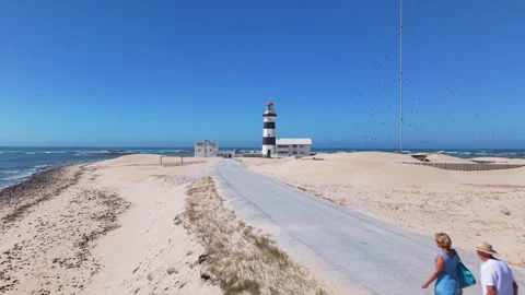 Drone Moving Forward Toward Lighthouse and Sea, Passing People Walking on Road Stock Footage 306292849
