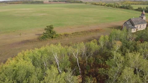 Drone moving forwards over a green forest and into a stony farm field.  Stock Footage 139872882