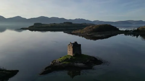 Drone moving left and backward from island castle in Scotland 動画素材 334459221