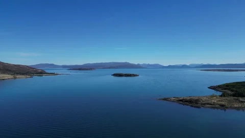 Drone moving left over lake and islands in Scotland 動画素材 334458497