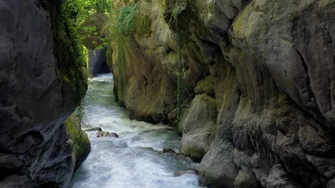Drone moving over flowing river amidst rock formation in forest - Stock Footage 119307887