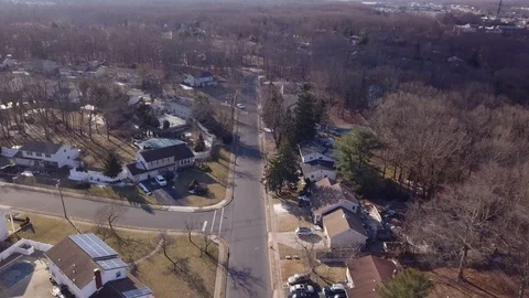Drone moving over housing road as two cars drive by 動画素材 104147264