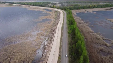 Drone moving over a road between two lakes with dramatic clouds in background Stock Footage 154825595