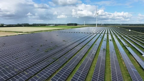 Drone moving over solar panel farm towards wind turbine farm blue sky Stock Footage 343244756