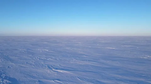 Drone moving quickly low above an extensive flat area covered in snow Stock Footage 246002028